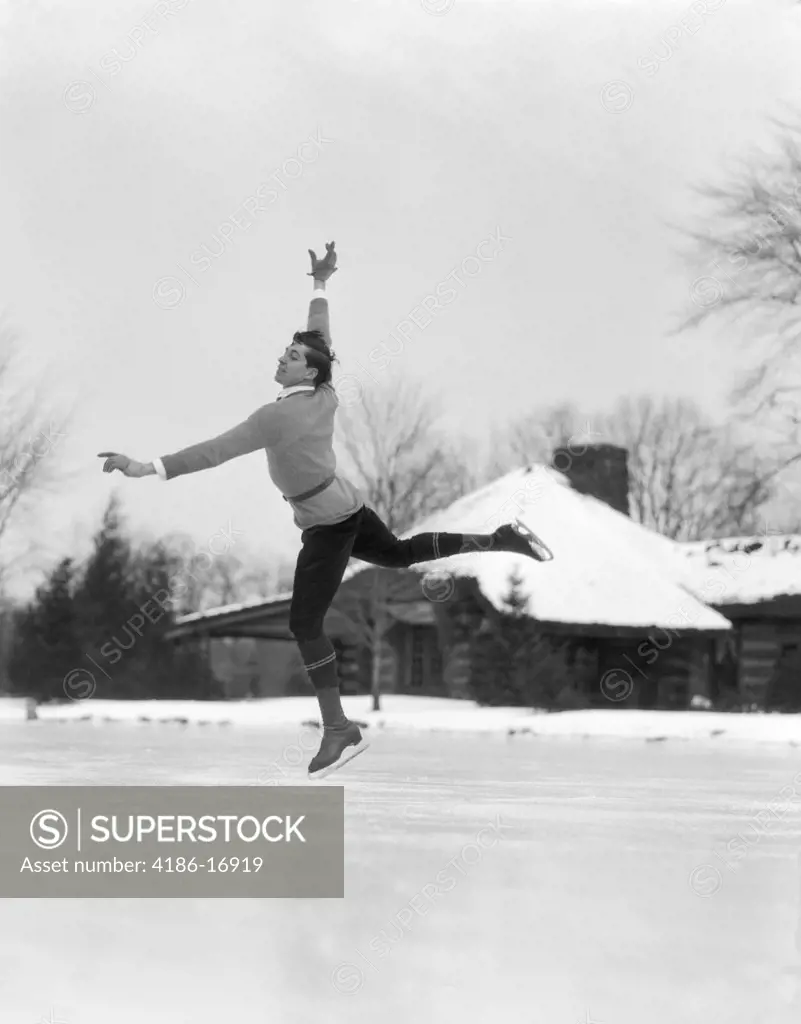 1920S 1930S Man Ice Skating On Outdoor Ice Rink Doing An Arabesque With One Toe Point On Ice Other Leg And Hands Extended