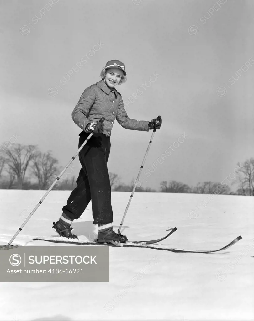 1940S 1950S Woman Smiling At Camera On Wood Skis With Bamboo Ski Pole In Each Hand Wearing Quilted Jacket