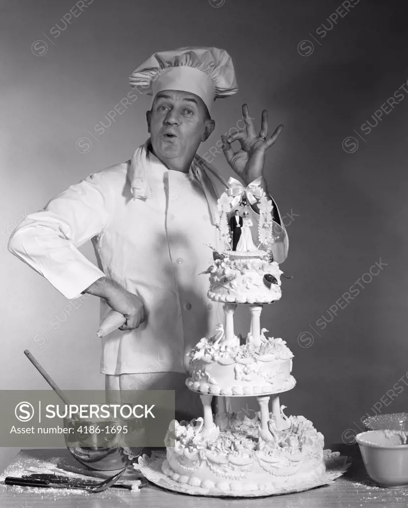 Man Portrait Baker Making Ok Success Hand Sign Next To Three Tier Wedding Cake Bride And Groom On Top