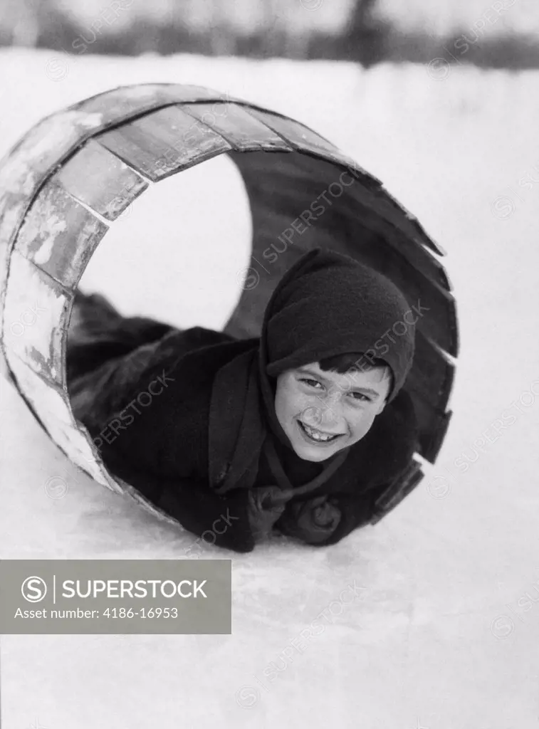1920S Boy Playing Lying In Snow Rolling In Wooden Barrel