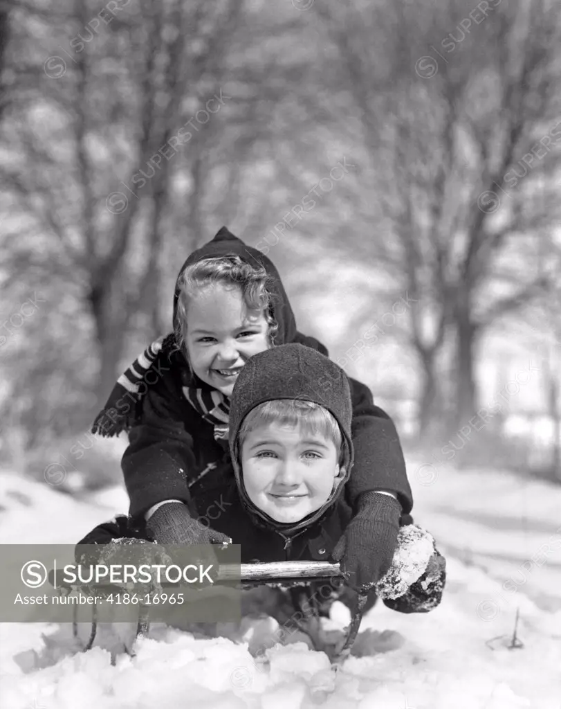 1930S Smiling Boy And Girl On Sled In Snow Looking At Camera