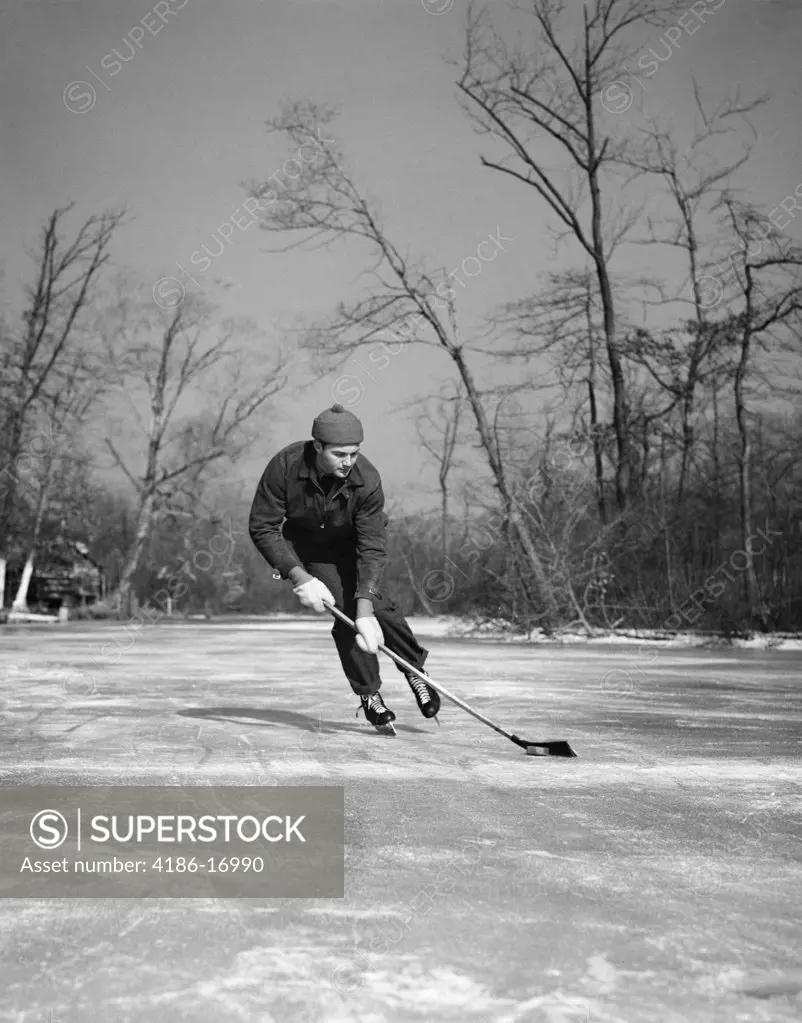 1940S Man Playing Ice Hockey On Frozen Lake Controlling Puck With Stick