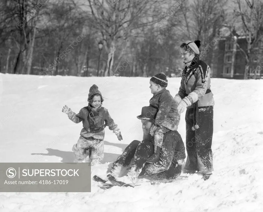 1930S Man & Woman With A Boy & Girl Dressed In Winter Clothing Playing With Sled In Snow Field