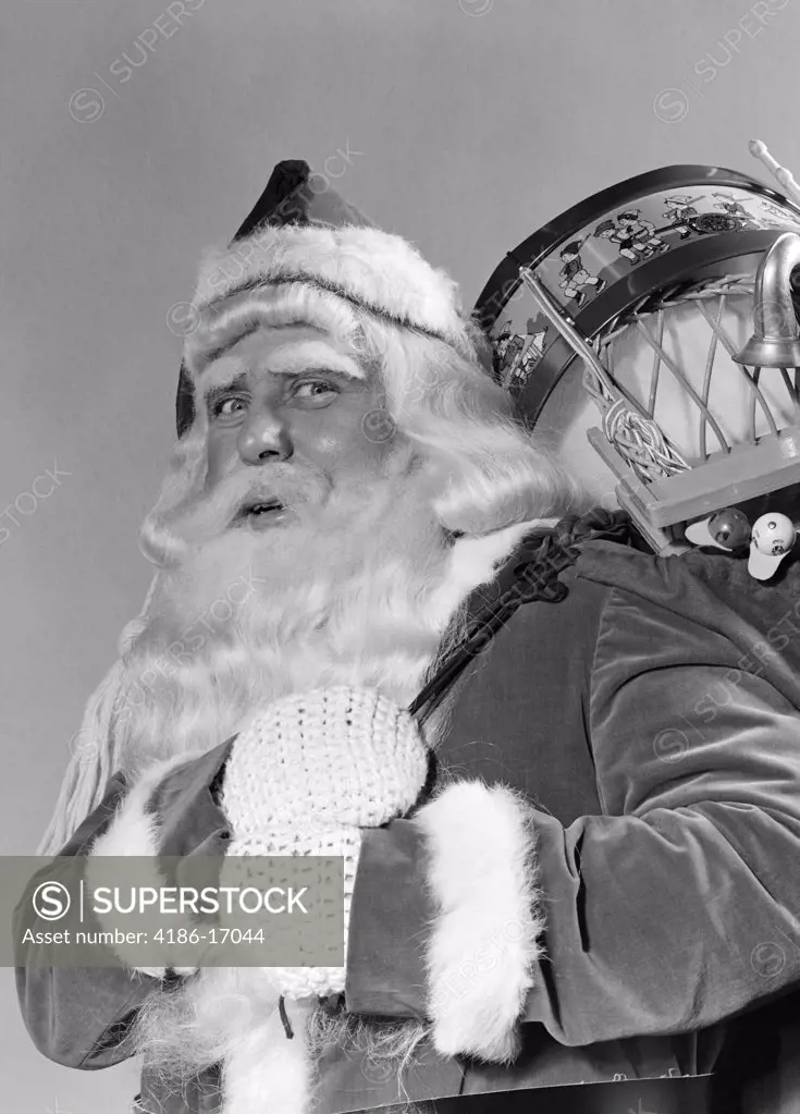 1940S Portrait Of Smiling Santa Claus With A Sack For Of Toy Presents Slung Over His Shoulder Looking At Camera