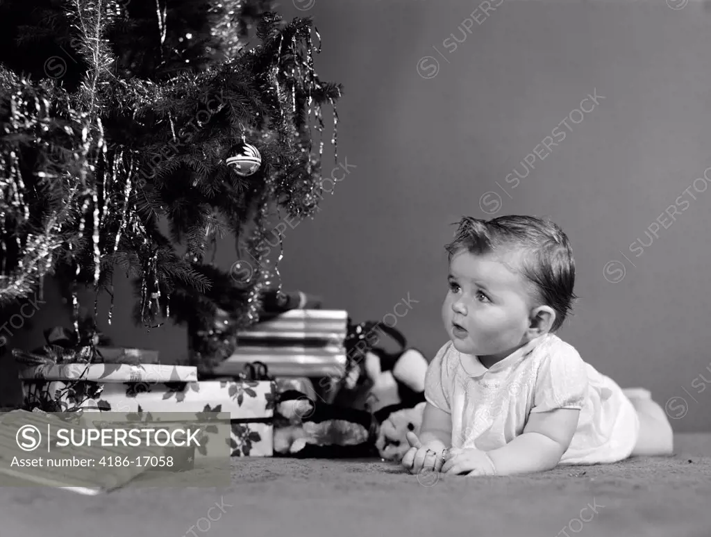 1940S Baby Laying In Front Of Christmas Tree And Christmas Presents