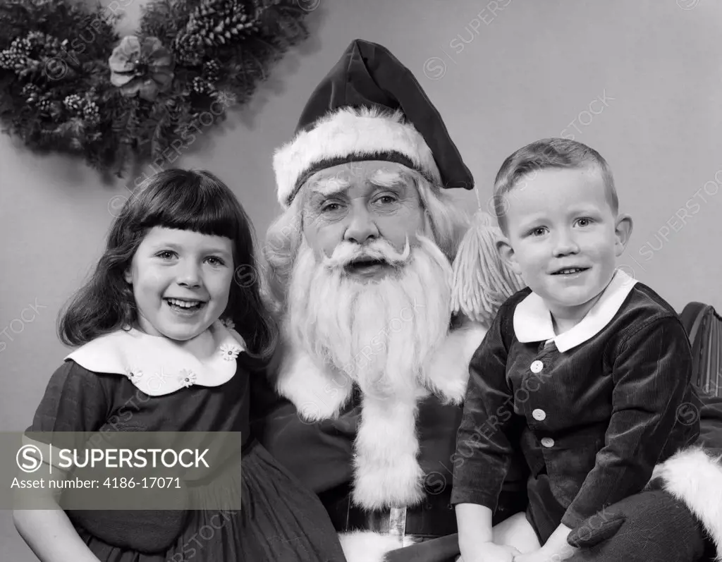 1950S Man Santa Claus Posing With Young Boy And Girl On Lap Smiling Indoor