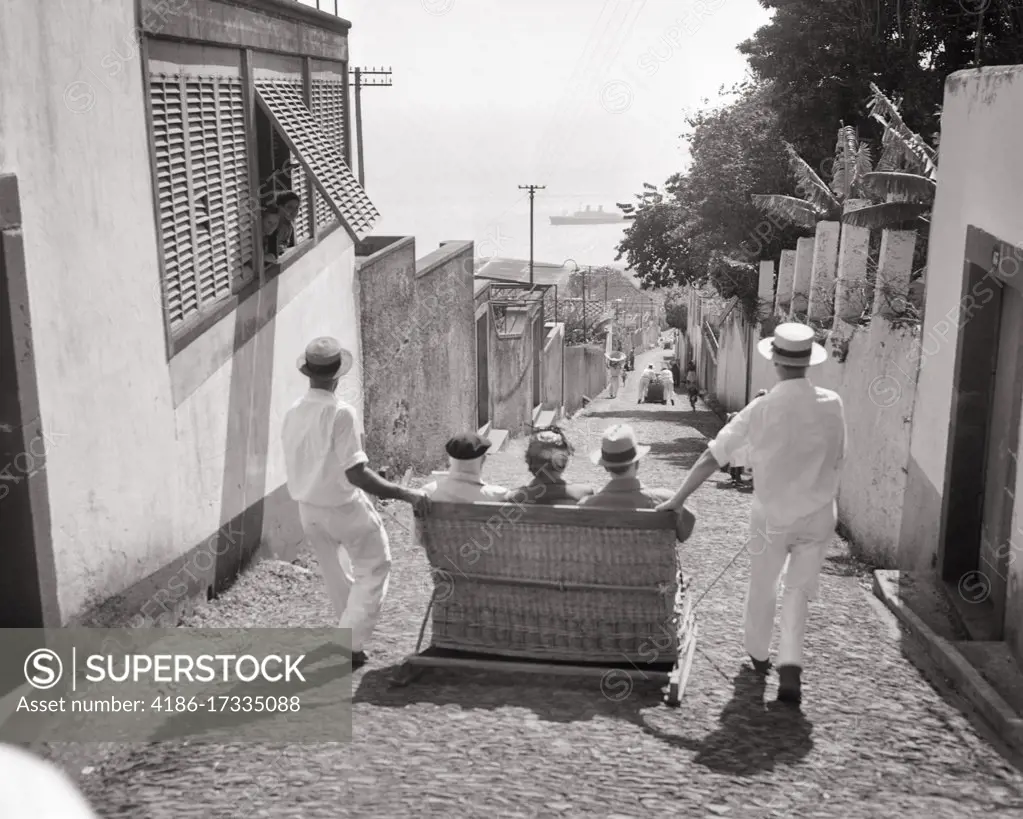 1950s TWO MEN CARREIROS CHAUFFEURS GUIDE THREE TOURISTS IN A MONTE SLEDGE WICKER TOBOGGAN RIDE TO FUNCHAL MADEIRA PORTUGAL 
