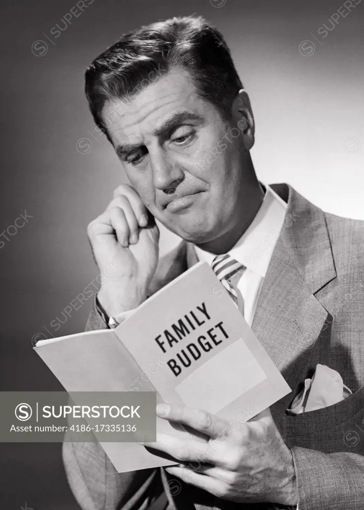 1950s MAN HUSBAND FATHER HOMEOWNER TAX PAYER WITH TROUBLED FACIAL EXPRESSION NERVOUSLY TUGGING EAR REVIEWING HIS FAMILY BUDGET