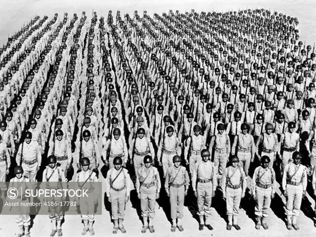 1940s WWII LARGE FORMATION U.S. ARMY INFANTRY SOLDIERS AT ATTENTION WEARING HELMETS UNDER ARMS RANK AND FILE