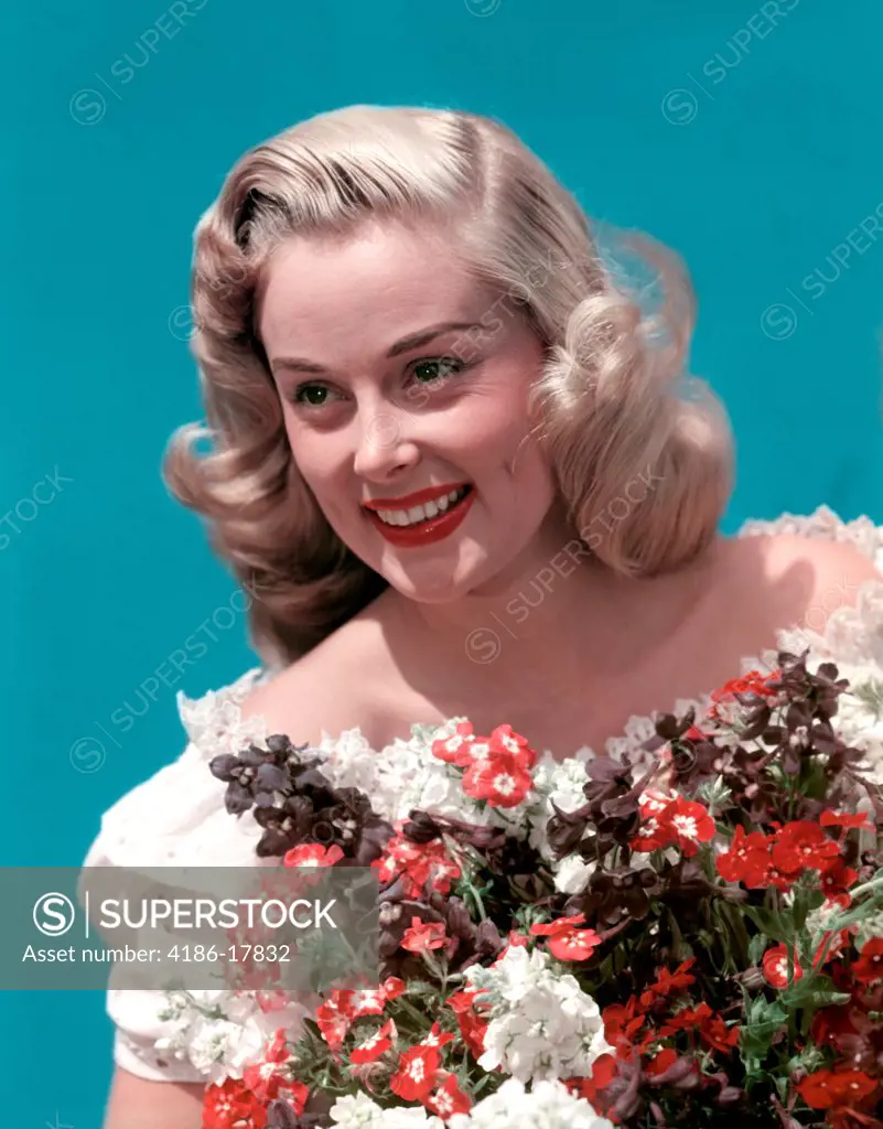1940s PORTRAIT SMILING BLOND TEEN GIRL WEARING OFF THE SHOULDER LACE BLOUSE HOLDING BOUQUET OF SPRING FLOWERS