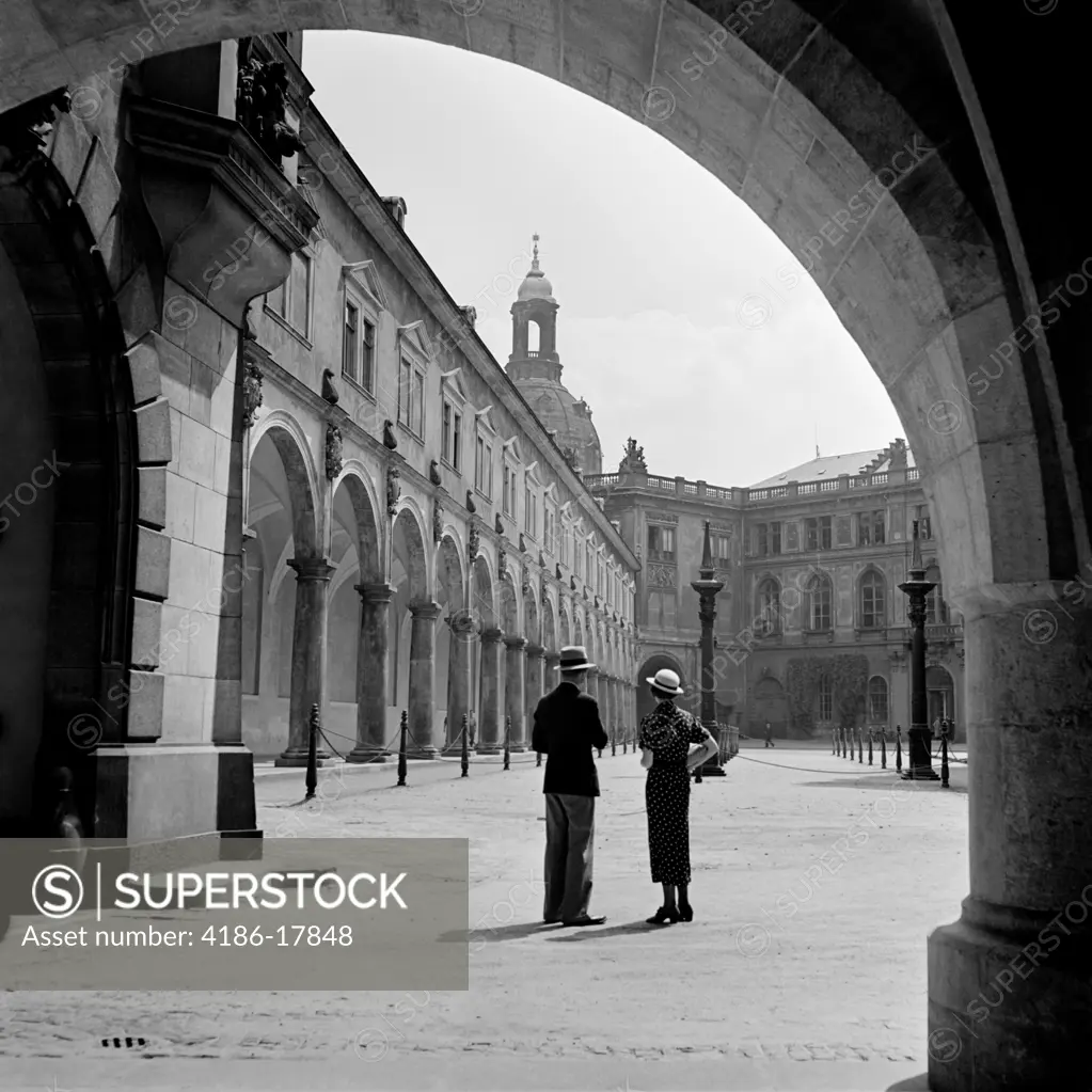 1930s FASHIONABLE COUPLE STANDING IN COURTYARD OF AN OLD CASTLE DRESDEN GERMANY