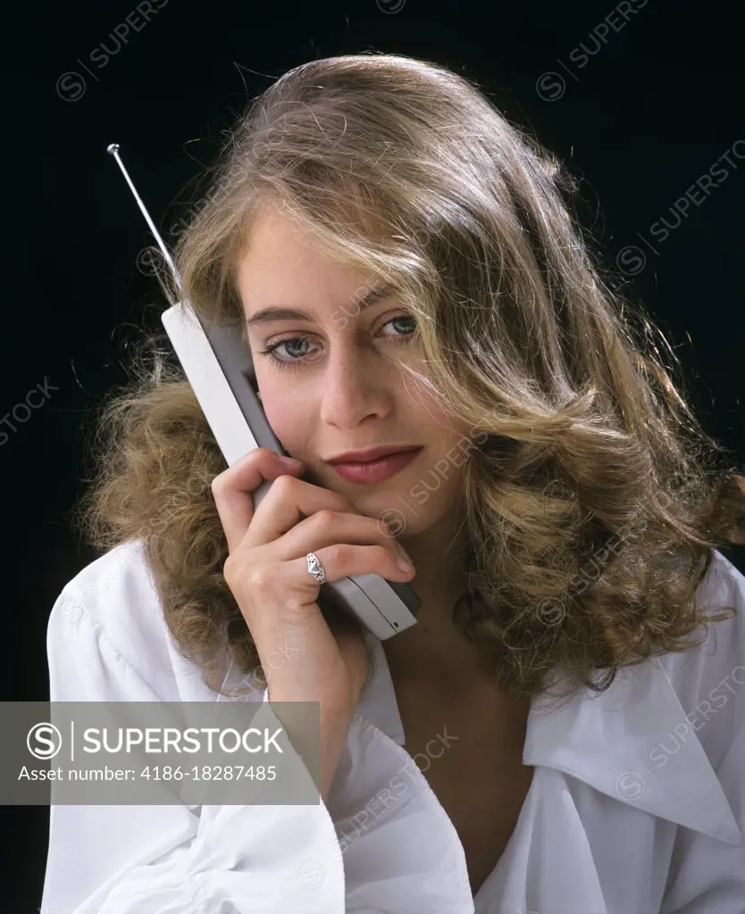 1990s TEENAGE GIRL TALKING LISTENING ON EARLY STYLE PERSONAL CELLULAR MOBILE TELEPHONE