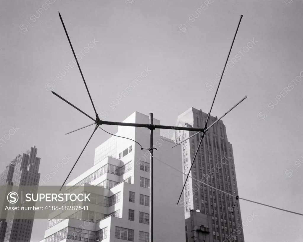 1950s 1960s TELEVISION ANTENNA BESIDE TALL SKYSCRAPER BUILDINGS