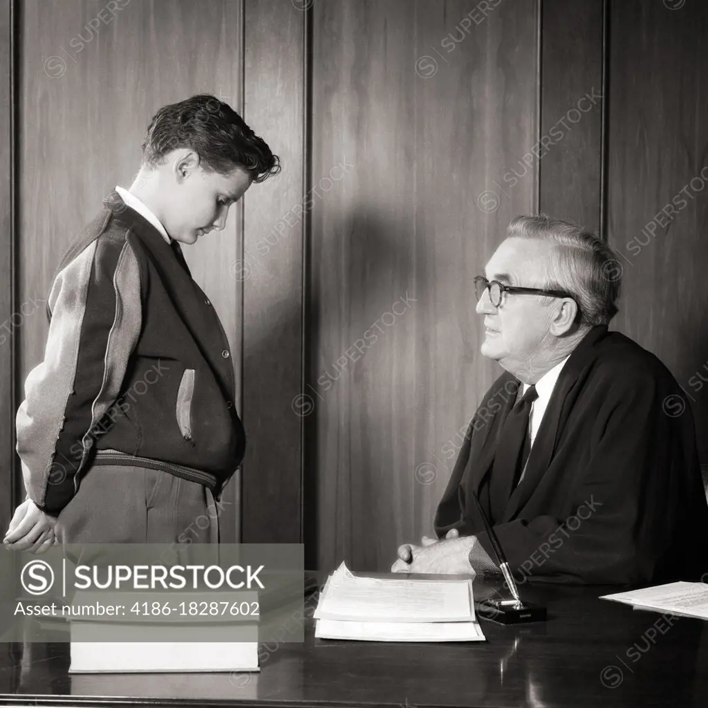 1940s 1950s TEENAGE BOY HEAD LOWERED IN SHAME TALKING TO JUDGE A SENIOR MAN