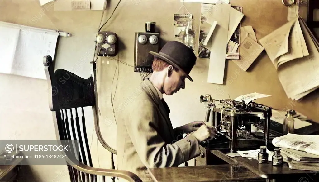 1920s ANONYMOUS MAN WEARING BOWLER HAT TYPING IN OFFICE