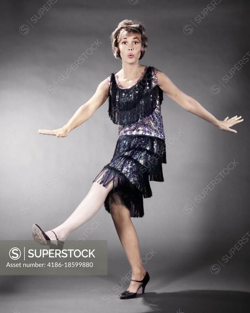 1960s WOMAN IN FRINGED FLAPPER DRESS COSTUME DANCING LOOKING AT CAMERA