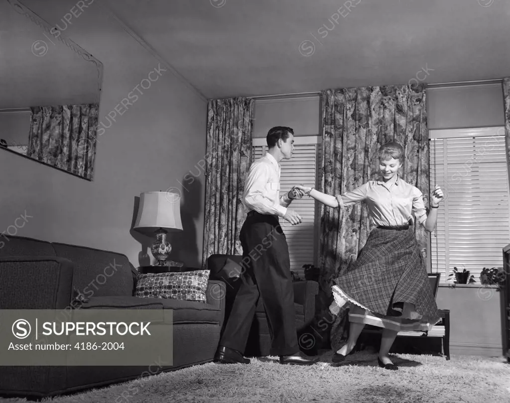 1950S Teen Couple Doing Jitterbug Rock And Roll Dance In Living Room Man Woman Boy Girl