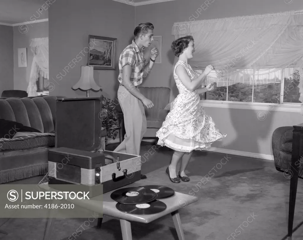 1950S Laughing Teenage Couple Dancing To The Phonograph Playing 33 Rpm Records In Living Room