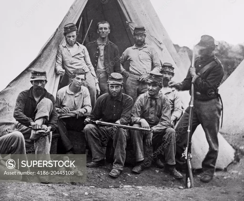 1860s GROUP OF NINE UNION SOLDIERS SEATED IN FRONT OF TENT HOLDING RIFLES LOOKING AT CAMERA