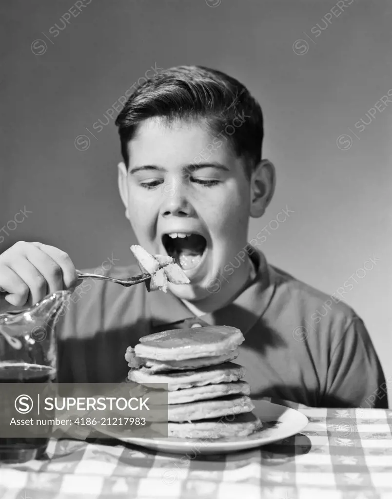 1960s BOY EATING STACK OF PANCAKES 