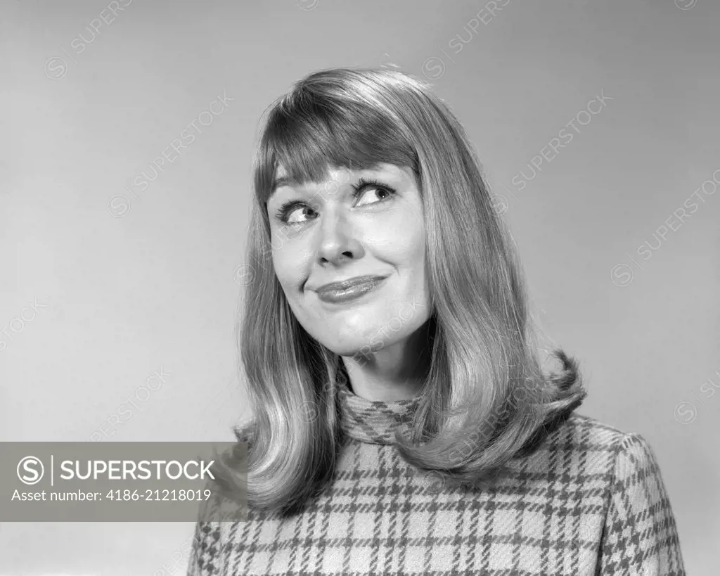 1960s WOMAN WITH LONG HAIR FLIP STYLE WITH BANGS LOOKING UP WITH AMUSED SMILE FACIAL EXPRESSION 