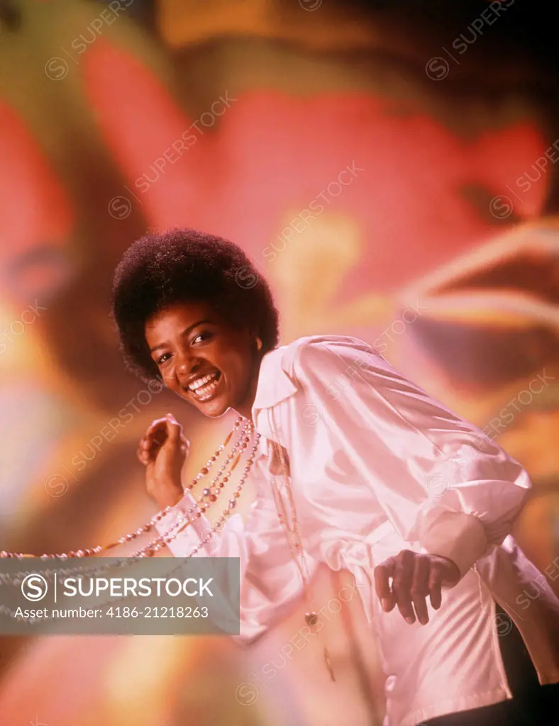 1970s LAUGHING YOUNG AFRICAN AMERICAN WOMAN AFRO HAIR STYLE WHITE SILK SHIRT SINGING DANCING BEADS SWINGING LOOKING AT CAMERA