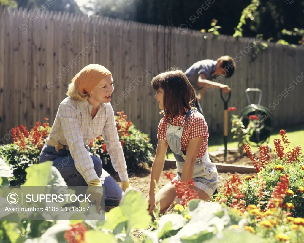 1970s MOTHER DAUGHTER AND SON GARDENING IN BACKYARD
