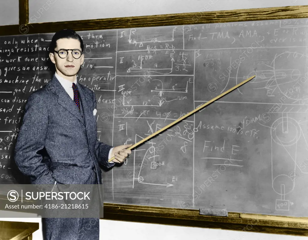  1930s 1940s MAN TEACHER PROFESSOR POINTING POINTER AT BLACKBOARD LOOKING AT CAMERA