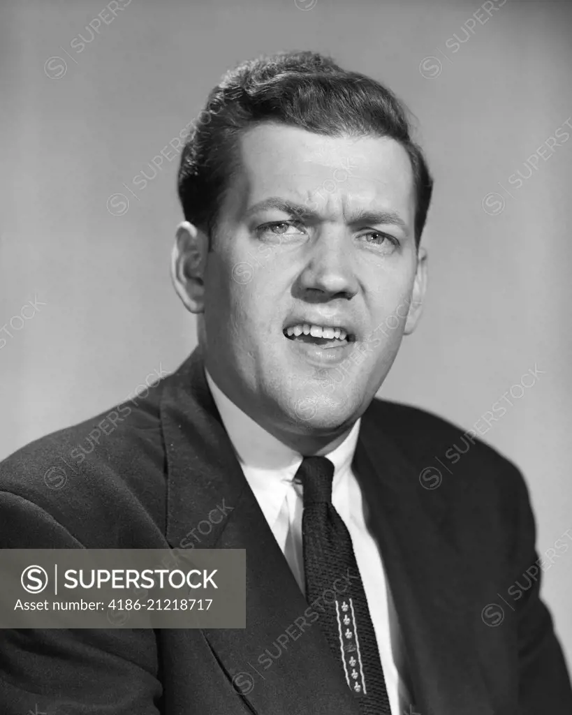 1950s MAN BUSINESS IN SUIT AND TIE MAKING SKEPTICAL FUNNY FACE EXPRESSION LOOKING AT CAMERA