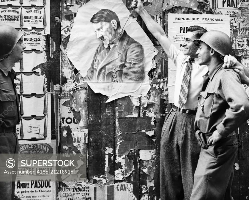 1940s CIVILIAN MAN SYMBOLICALLY HANGING ADOLF HITLER AS TWO YANK SOLDIERS LOOK ON AUGUST 26 1944 IN LATIN QUARTER PARIS FRANCE