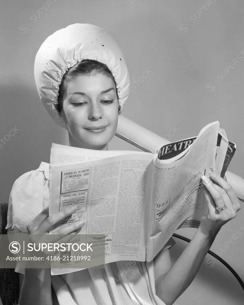 1960s WOMAN SITTING UNDER BONNET STYLE HAIRDRYER HAIR DRYER READING MAGAZINE 