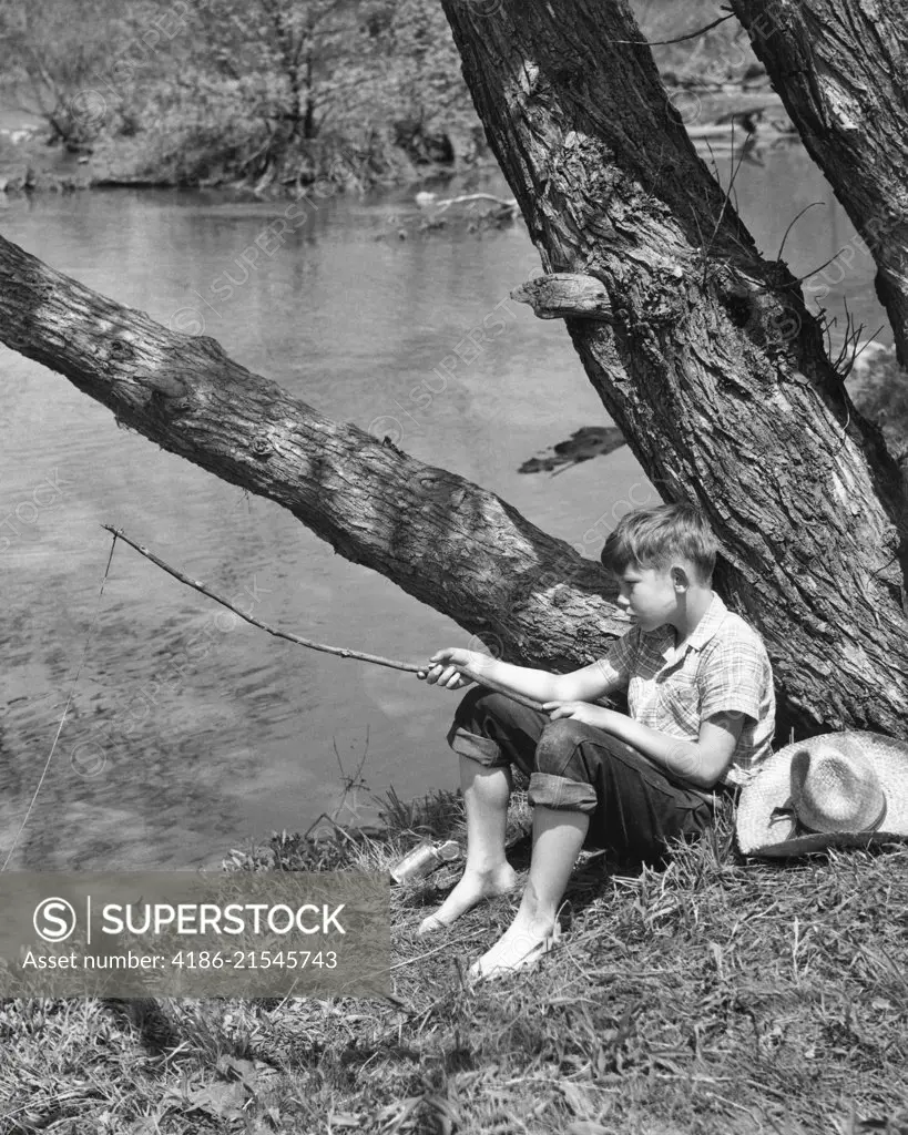 1940s BAREFOOT BOY SITTING UNDER TREE BY STREAM FISHING WITH TWIG POLE 