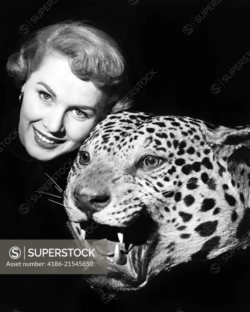 1950s SMILING WOMAN FACE LOOKING AT CAMERA POSED WITH GROWLING STUFFED LEOPARD HEAD