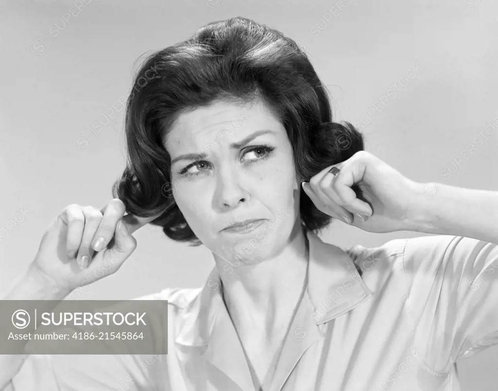 1960s BRUNETTE WOMAN STICKING FINGERS INTO HER EARS