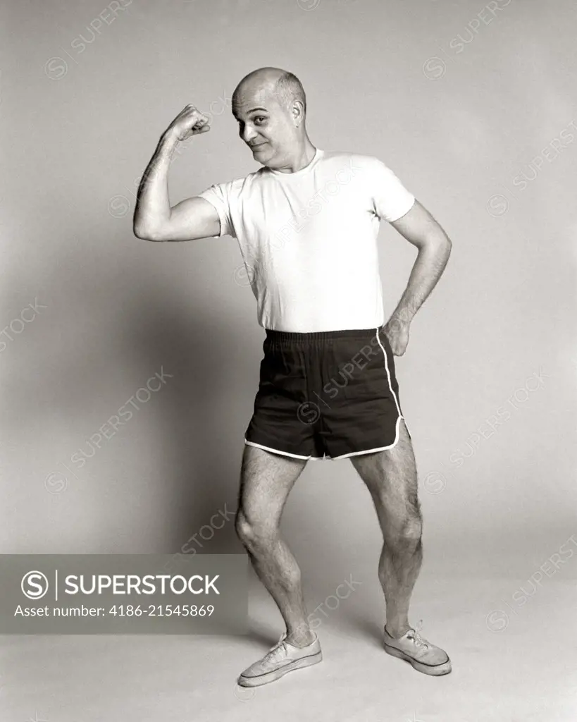 1970s MATURE MIDDLE AGED MAN IN EXERCISE GYM SHORTS TEE SHIRT BICEP POSE