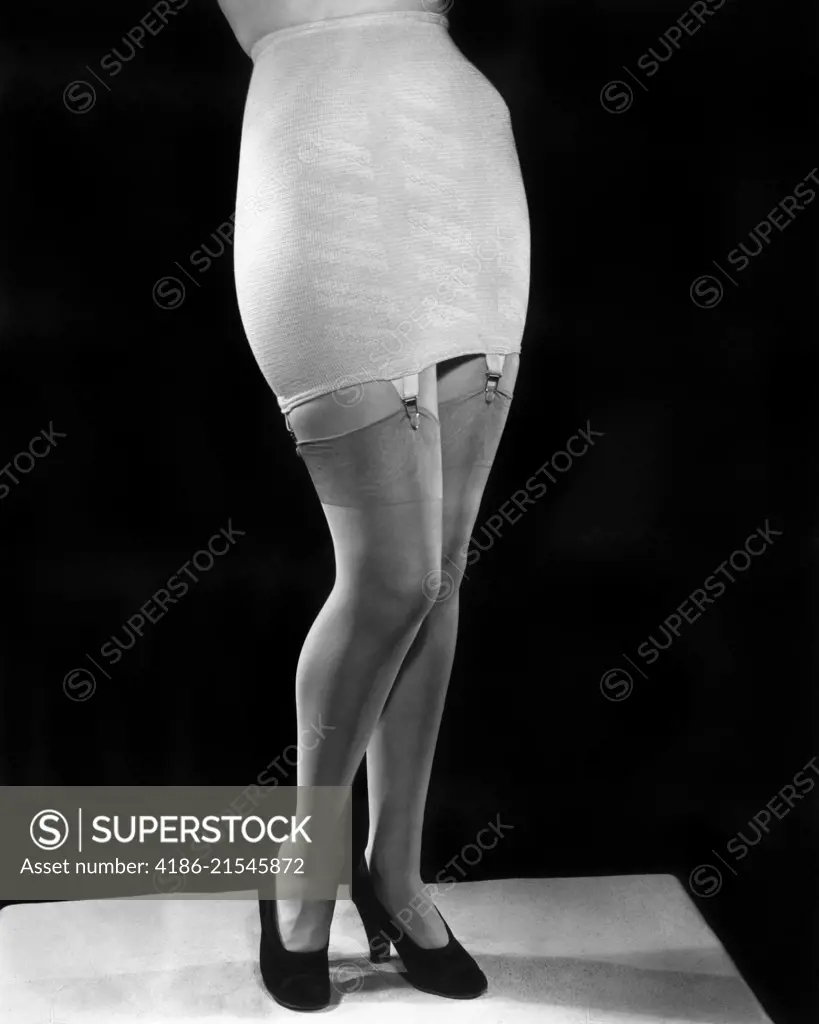 1940s FASHION WOMAN FROM WAIST DOWN WEARING GIRDLE WITH GARTERS CLIPS  HOLDING SILK NYLON HOSE STOCKINGS - SuperStock