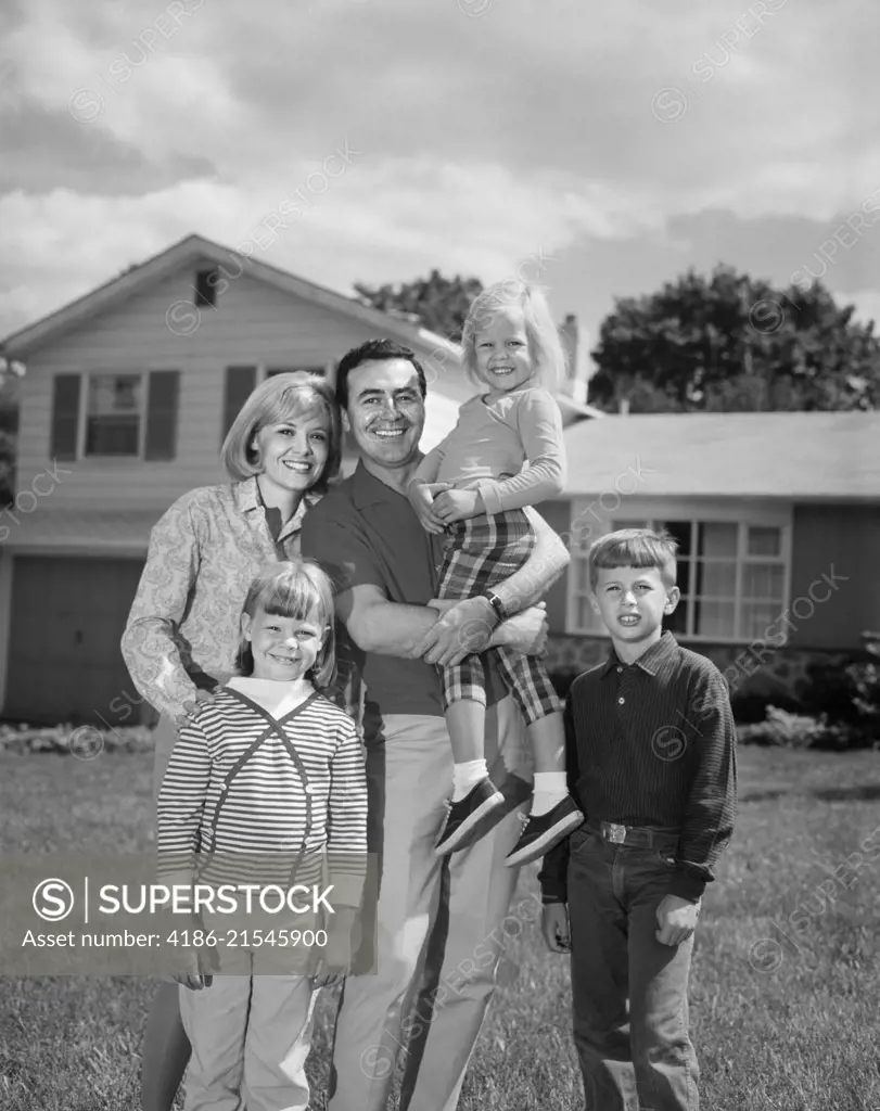 1960s 1970s FAMILY PORTRAIT OF FIVE POSED LOOKING AT CAMERA ON FRONT LAWN OF SUBURBAN HOUSE