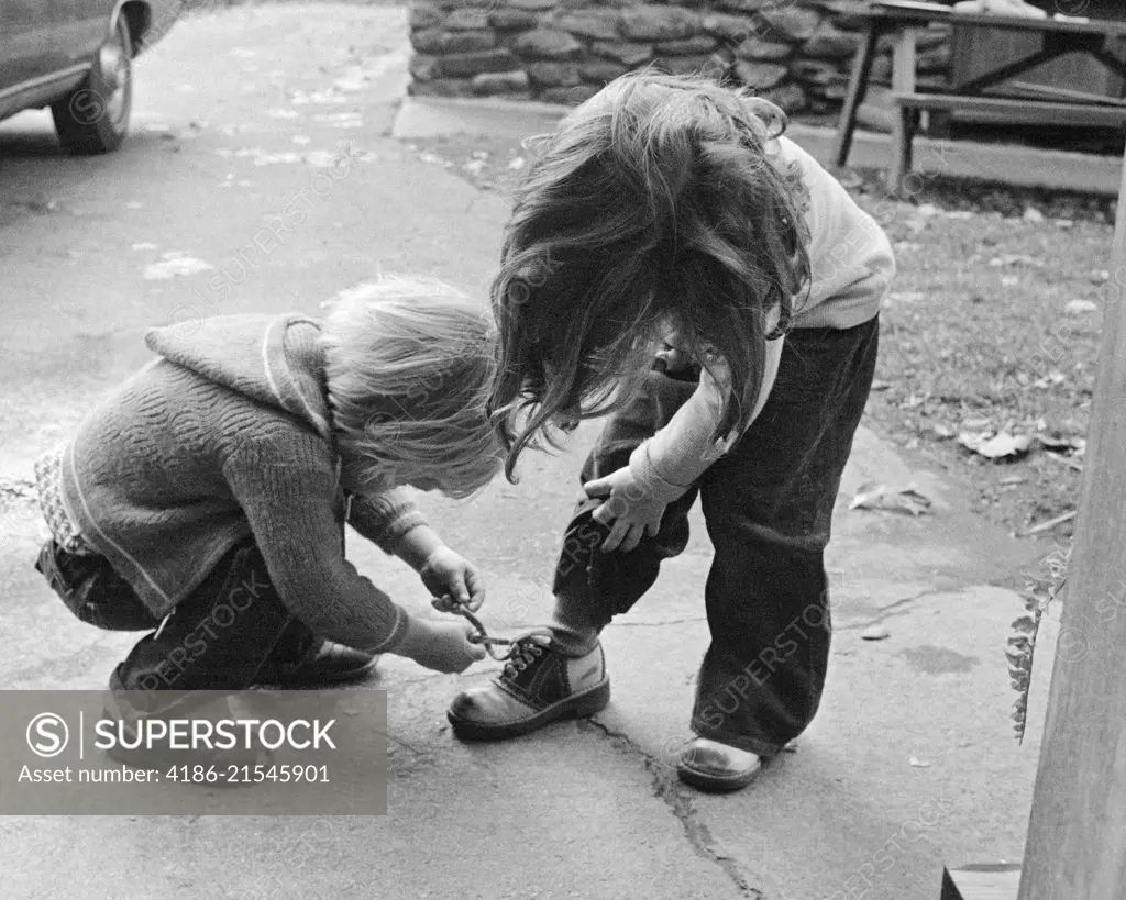 1970s 1970s BLOND BOY BENDING OVER HELPING GIRL TIE HER SHOE 