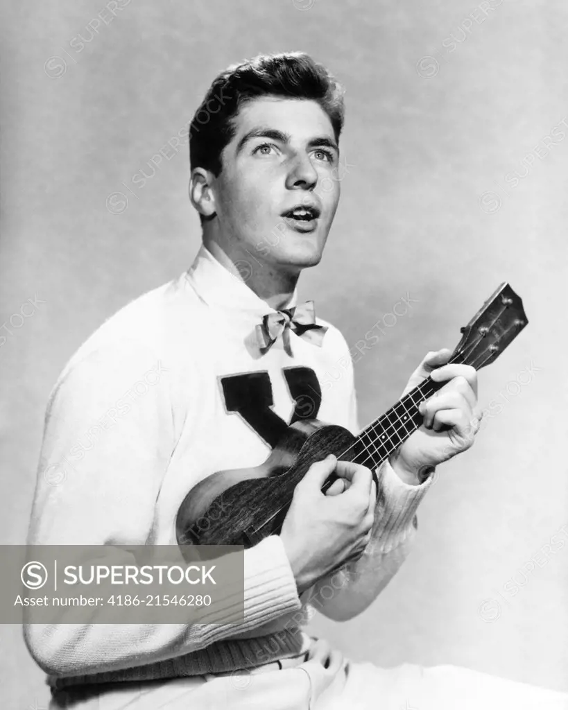 1940s 1950s COLLEGE BOY WEARING X LETTER SWEATER SINGING AND PLAYING UKULELE
