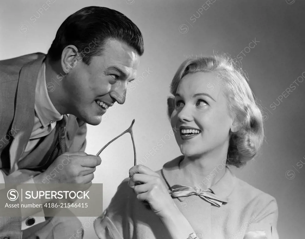 1950s COUPLE PULLING AND BREAKING A WISHBONE FOR LUCK TRADITION 