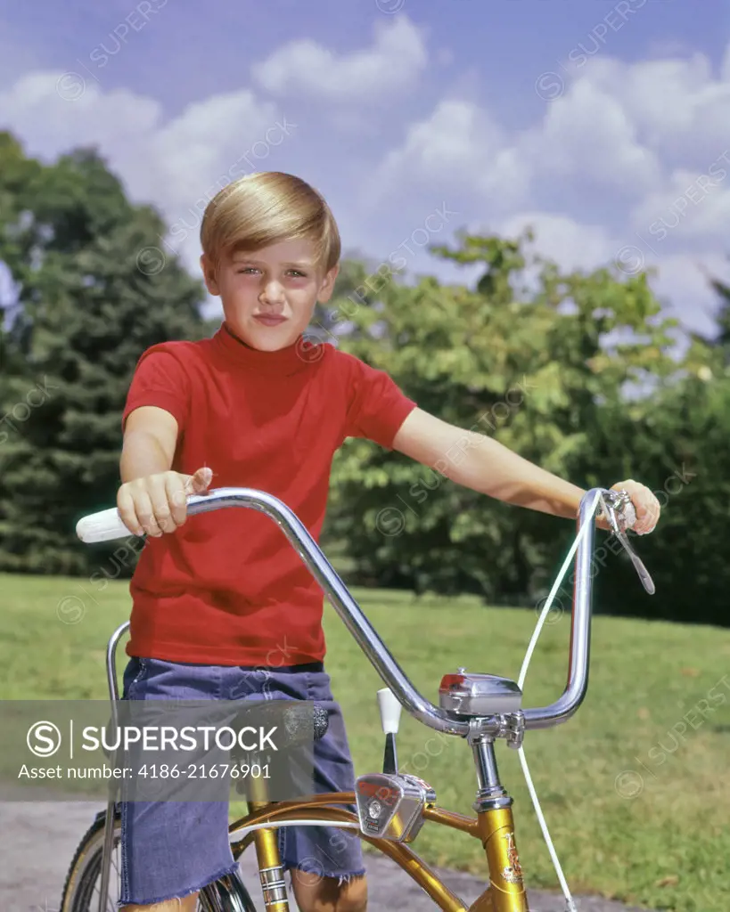 1960s PORTRAIT BOY BLOND WEARING RED SHIRT SITTING ON BIKE WITH PYRAMID CRUISER HANDLEBARS LOOKING AT CAMERA
