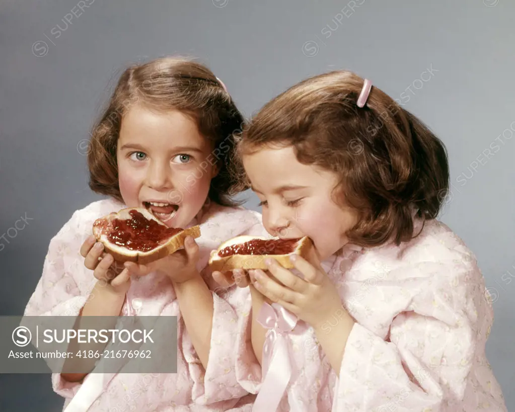 1960s TWIN BRUNETTE GIRLS EATING SLICES OF BREAD AND JELLY