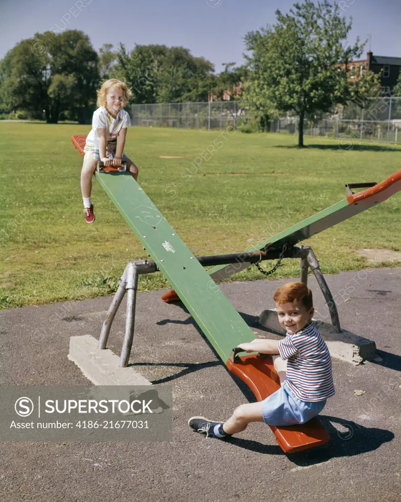 1960s BOY GIRL PLAYGROUND SITTING ON SEESAW SEE-SAW TEETER-TOTTER 