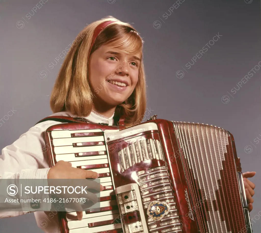 1960s 1970s SMILING BLOND TEENAGE GIRL MUSICIAN PERFORMER PLAYING ACCORDION MUSICAL INSTRUMENT