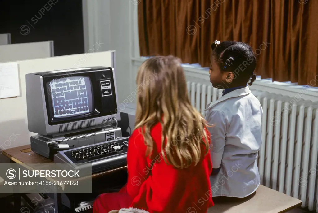 1980s TWO GIRLS LEARNING ABOUT COMPUTERS BY PLAYING ON SCREEN GAME