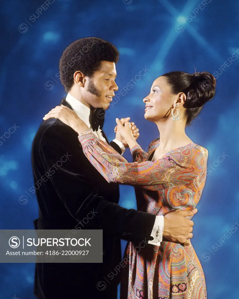 1970s AFRICAN AMERICAN COUPLE IN EVENING DRESS SLOW DANCING TOGETHER