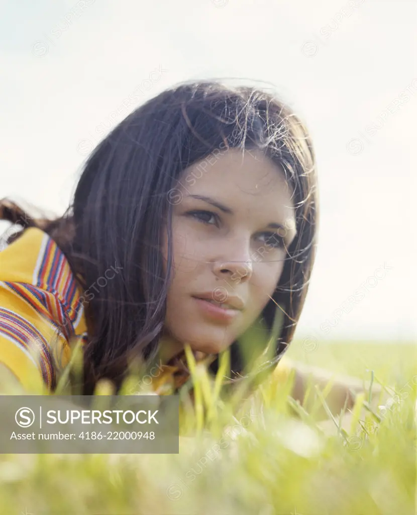 1970s PORTRAIT TEEN GIRL BRUNETTE LYING IN GRASS