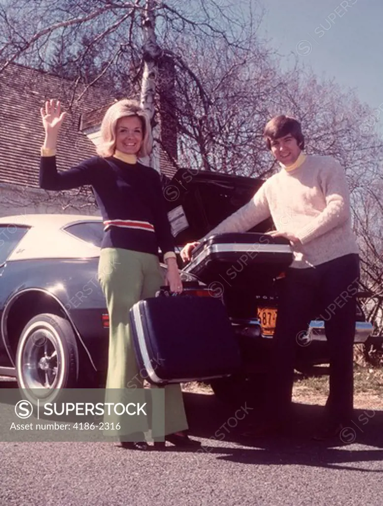 1960S Woman Waving Man Loading Suitcases Into Car