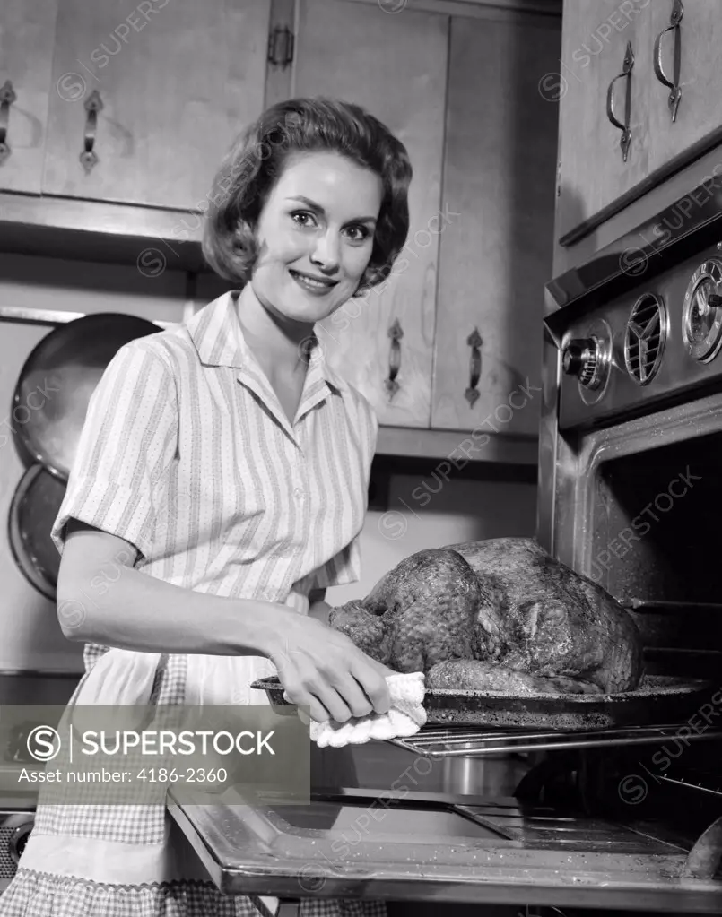 1960S Smiling Housewife Removing Thanksgiving Roast Turkey From Oven