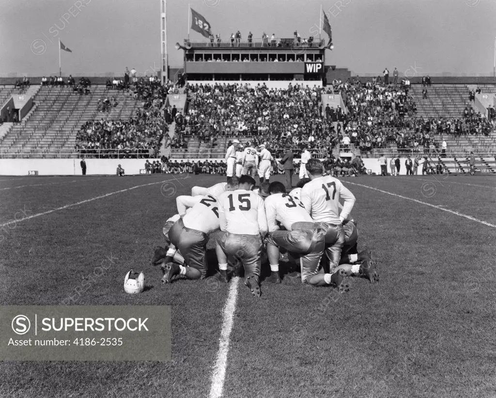 1940S 1950S School Football Players In Kneeling Huddle On Field